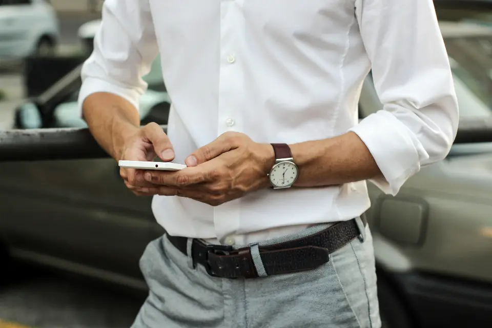 Vendedor revisando un pedido en su celular junto a su carro